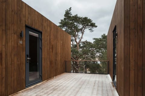 A building clad in dark vertical wood siding beside a wood deck