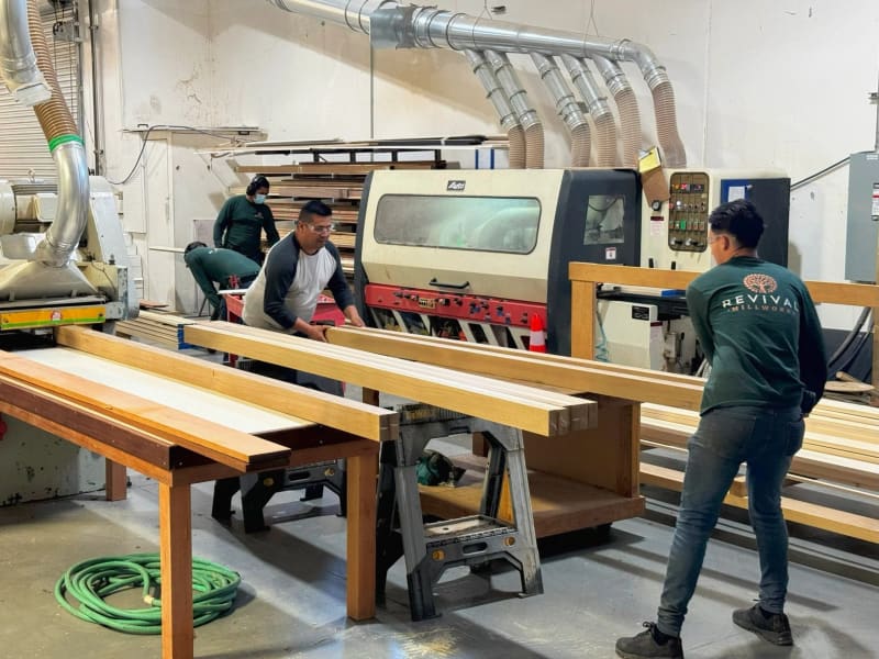 The Revival Millworks crew feeding boards through a moulder in the Livermore shop