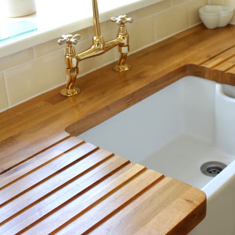 A wood countertop with drainboard grooves beside a farmhouse sink