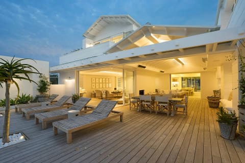 A wide wood deck with loungers outside a house